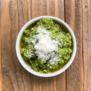 Small bowl of pesto with parmesan cheese.