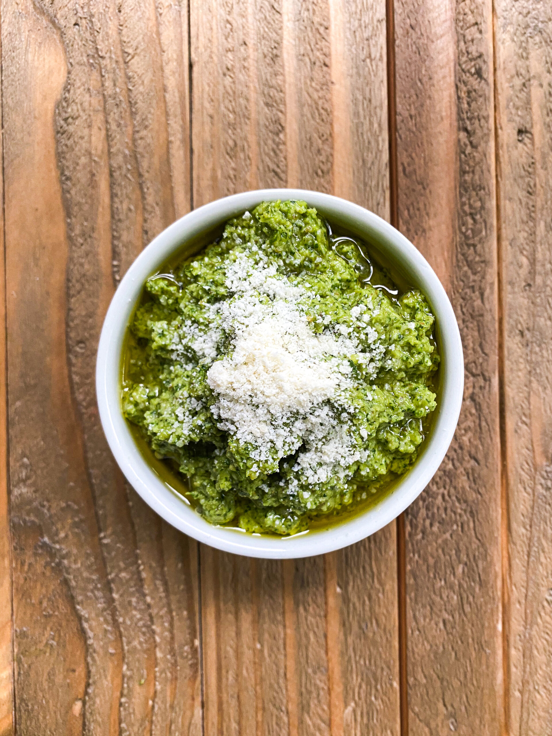 Small bowl of pesto with parmesan cheese.