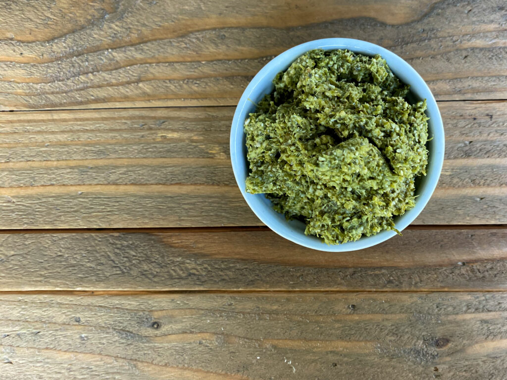 Pesto in white bowl on wood table.