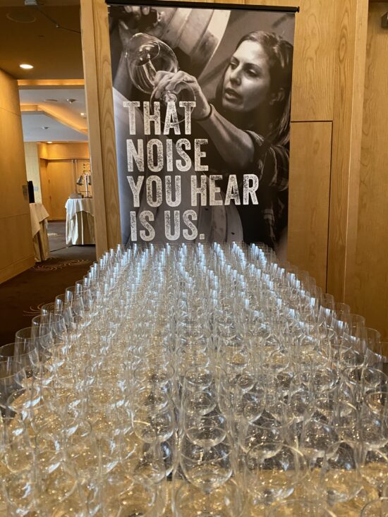 Wine glasses on a table with a poster above the table.