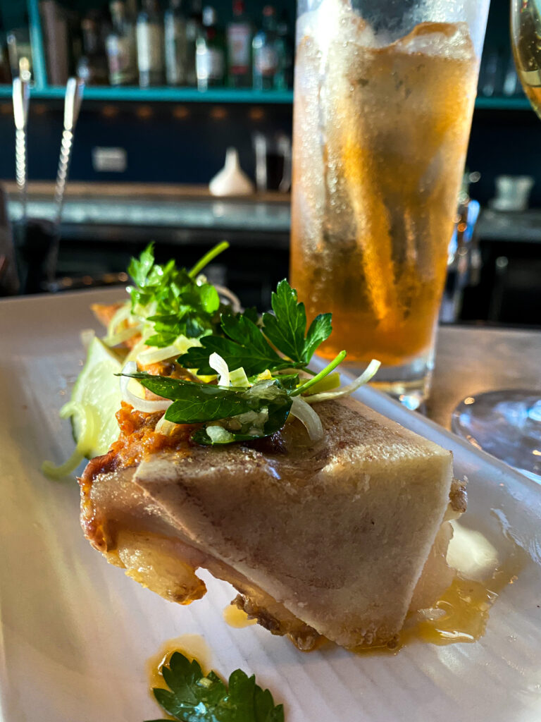 Bone marrow with garnishments on a white plate.