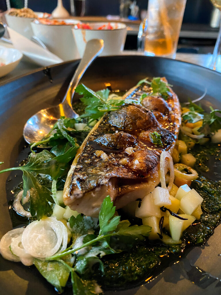 Bone marrow and garnishments on a black plate.