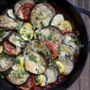 Eggplant, squash and peppers layered in a cast iron skillet.