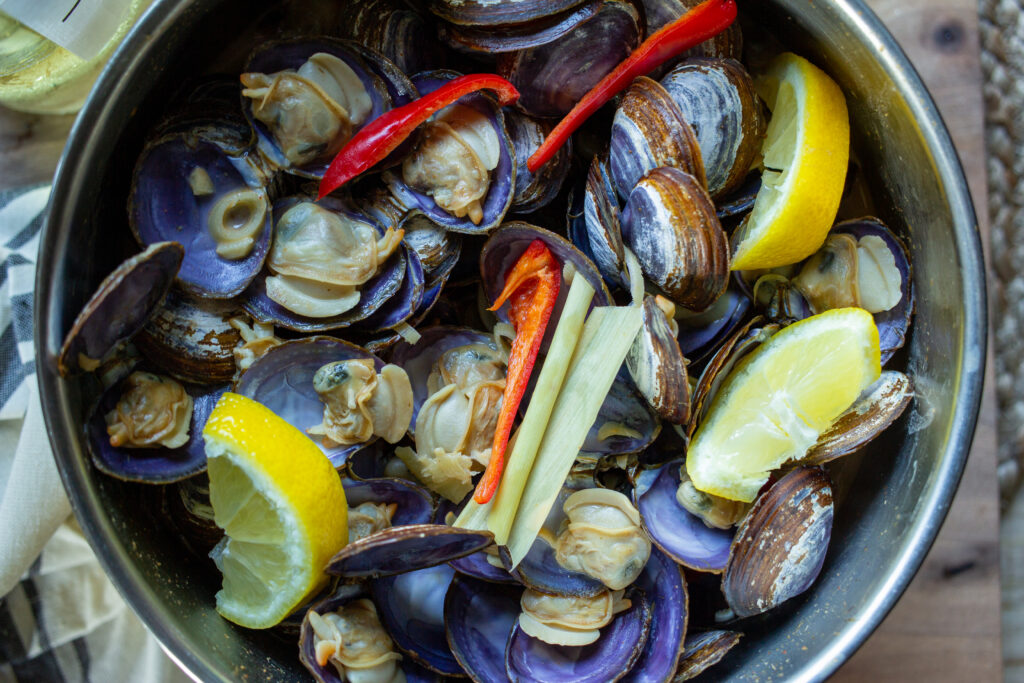 Clams with peppers, lemongrass, and lemon wedges.