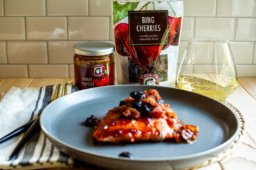 Roasted salmon next to a jar of BBQ sauce and a bag of dried cherries.