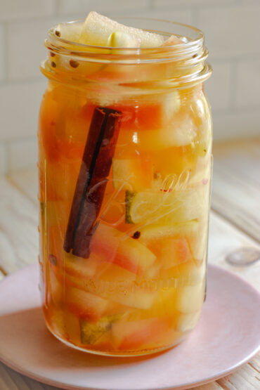 Pickled watermelon in a mason jar with a cinnamon stick.