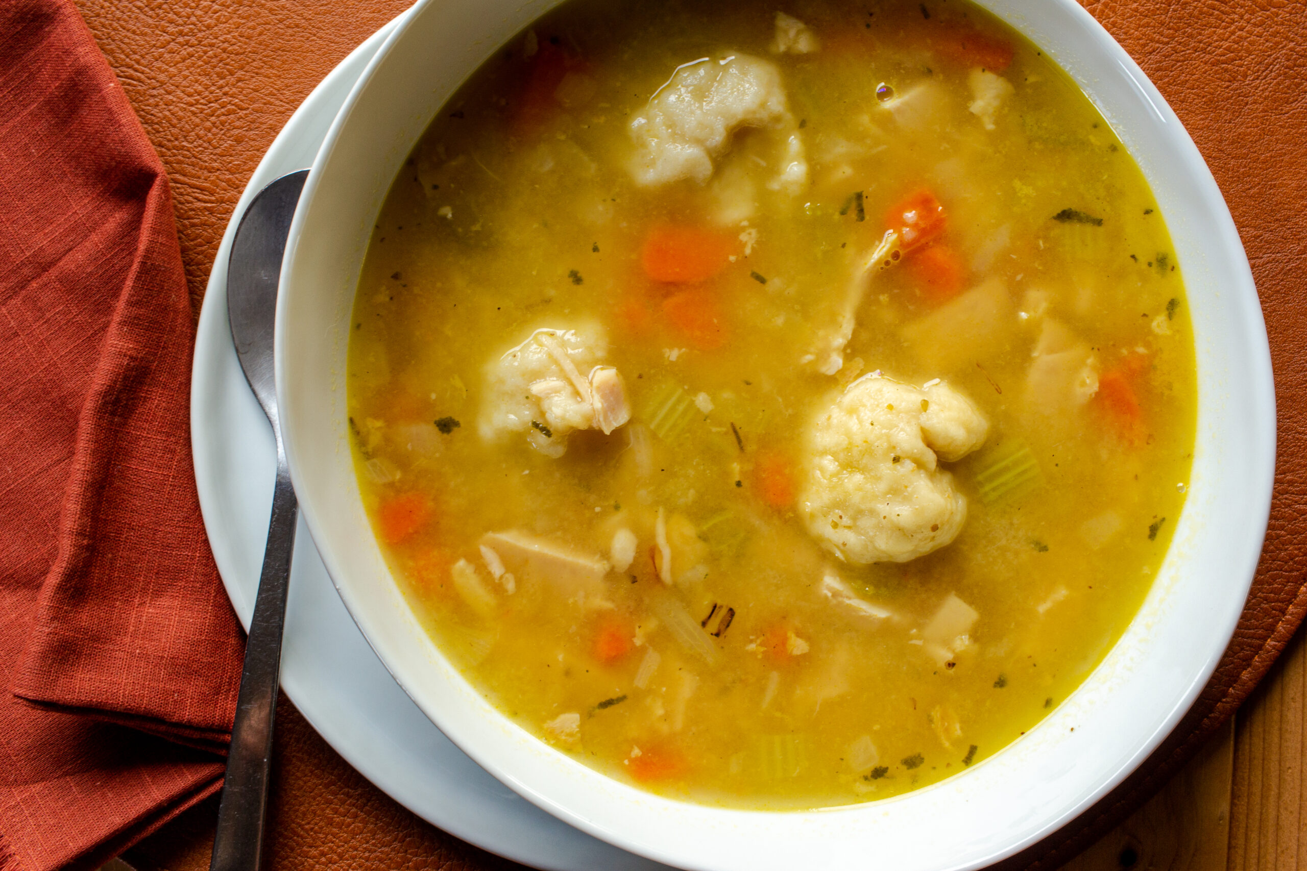 Bowl of turkey dumpling soup on a white plate.