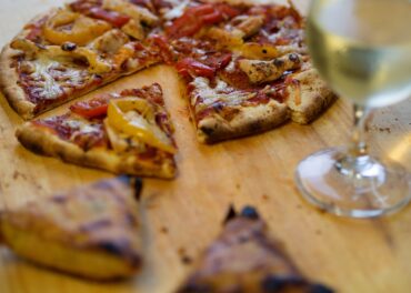 Pizza on a wood board with white wine.