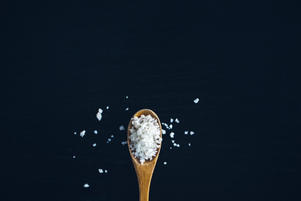 Wood spoon holding coarse salt that's spilling over.