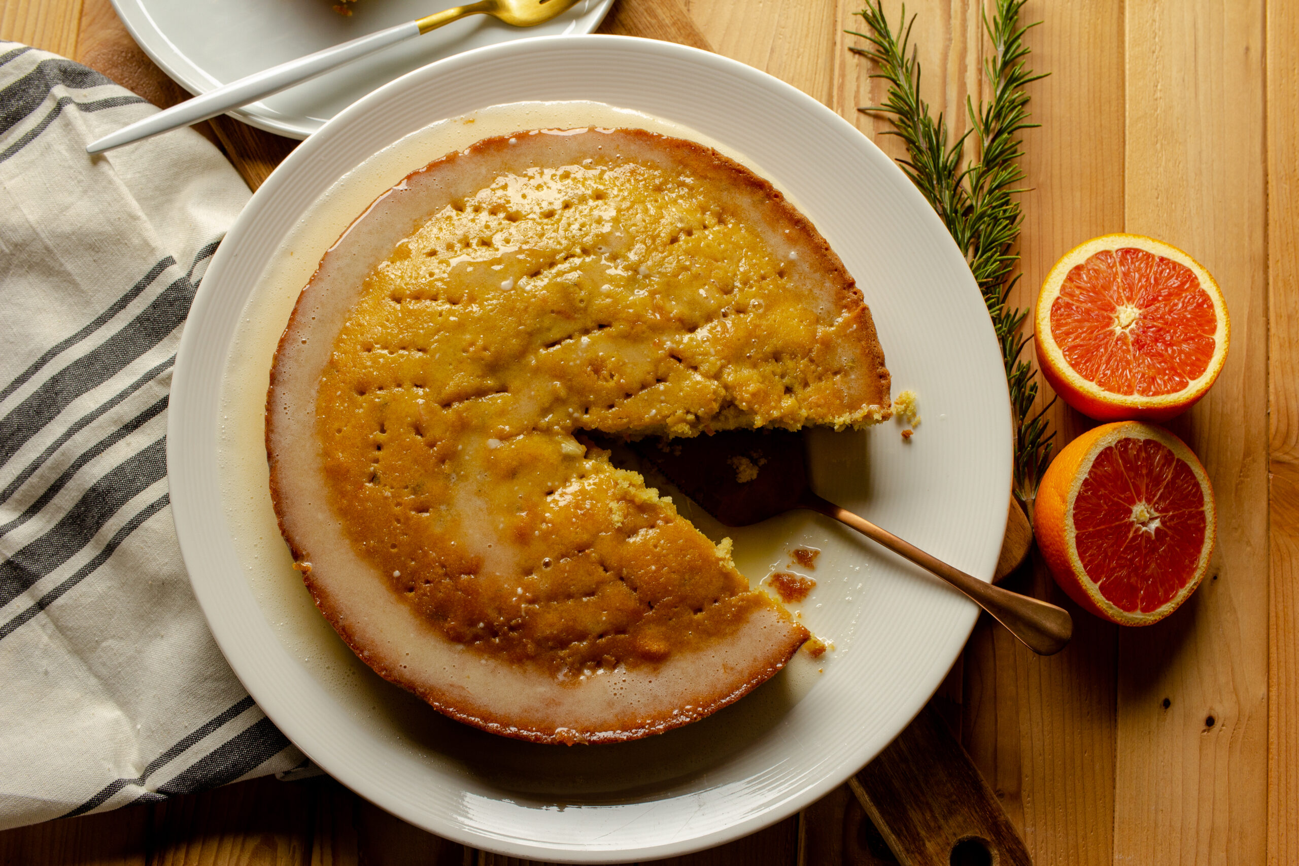 Orange olive oil cake covered in a glaze with a slice taken out.