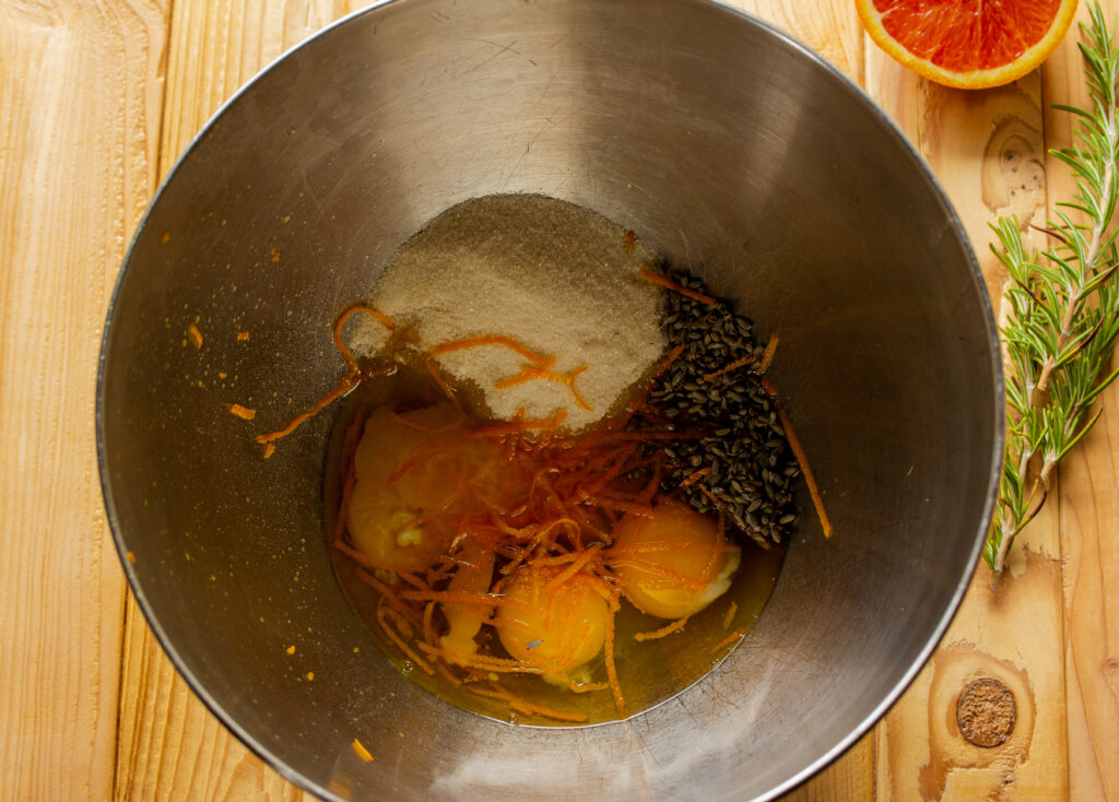 Mixer bowl filled with eggs, orange rind, lavender, and sugar.