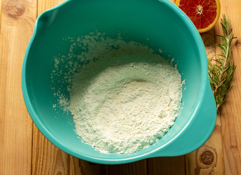 A blue mixing bowl filled with dry ingredients for a cake that have been mixed together.