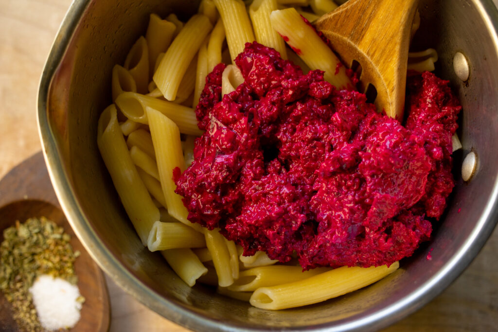 Sauce pot filled with cooked noodles and a creamy beet mixture.