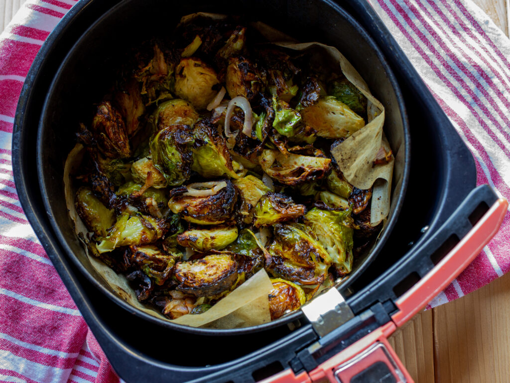 Air fryer brussels sprouts in an air fryer basket lined with parchment paper.