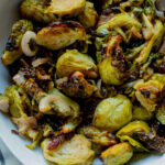 Close up of air fryer brussels sprouts with sliced shallots.