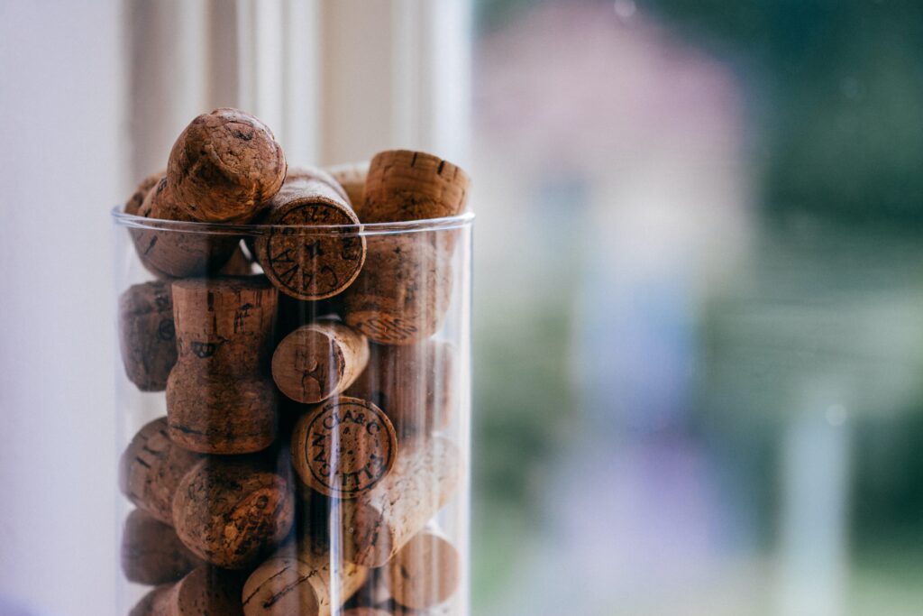 Champagne wine corks in a clear jar by a window.