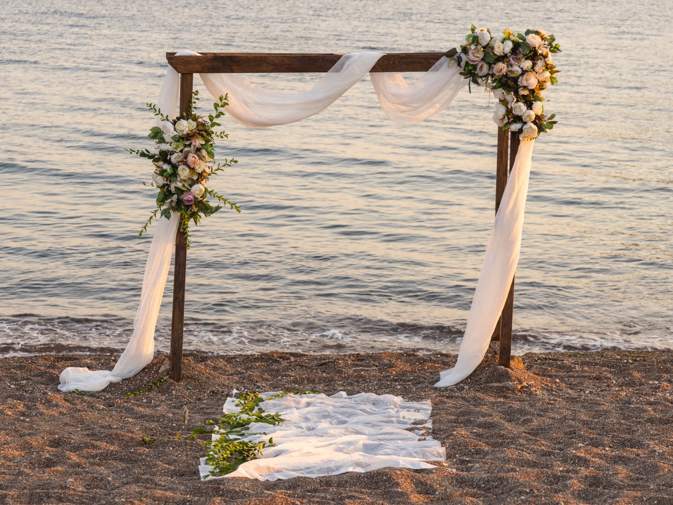 A wooden alter on a beach covered in flowers.