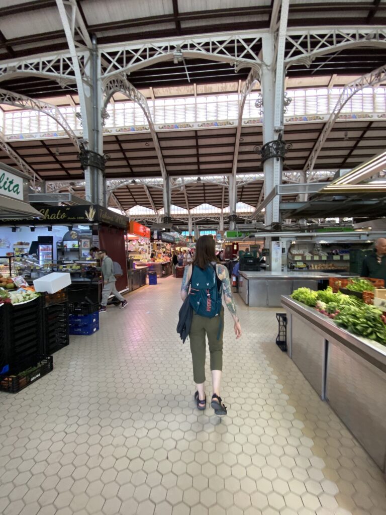 A girl walking through an indoor produce market.
