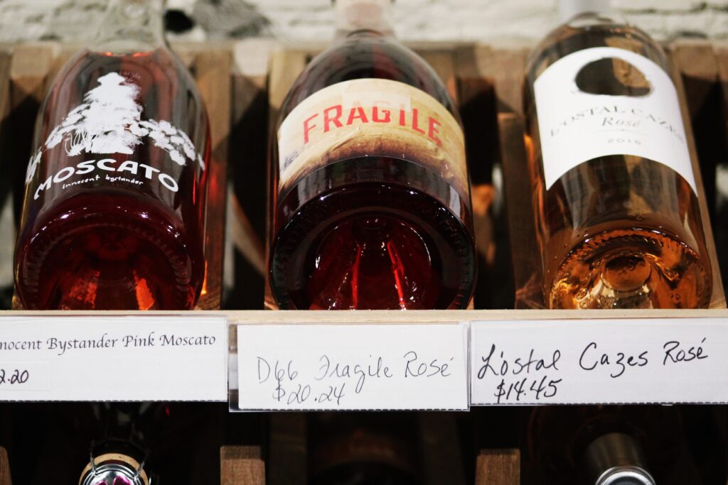 Three bottles of labeled wine horizontal on a wine shelf.
