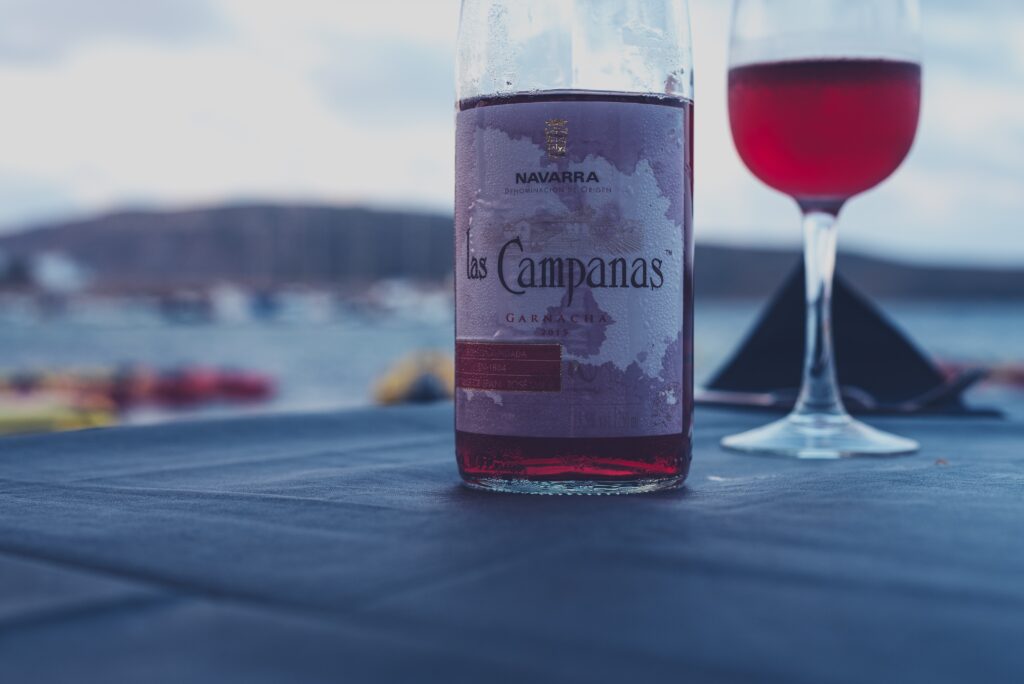 A half-empty bottle of rosé next to a glass of rosé wine.