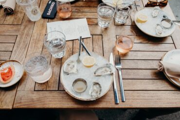 A plate of oysters next to water glasses and a glass of rosé wine.