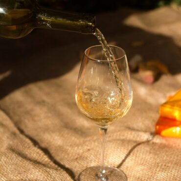 A bottle of white wine being poured into a wine glass.